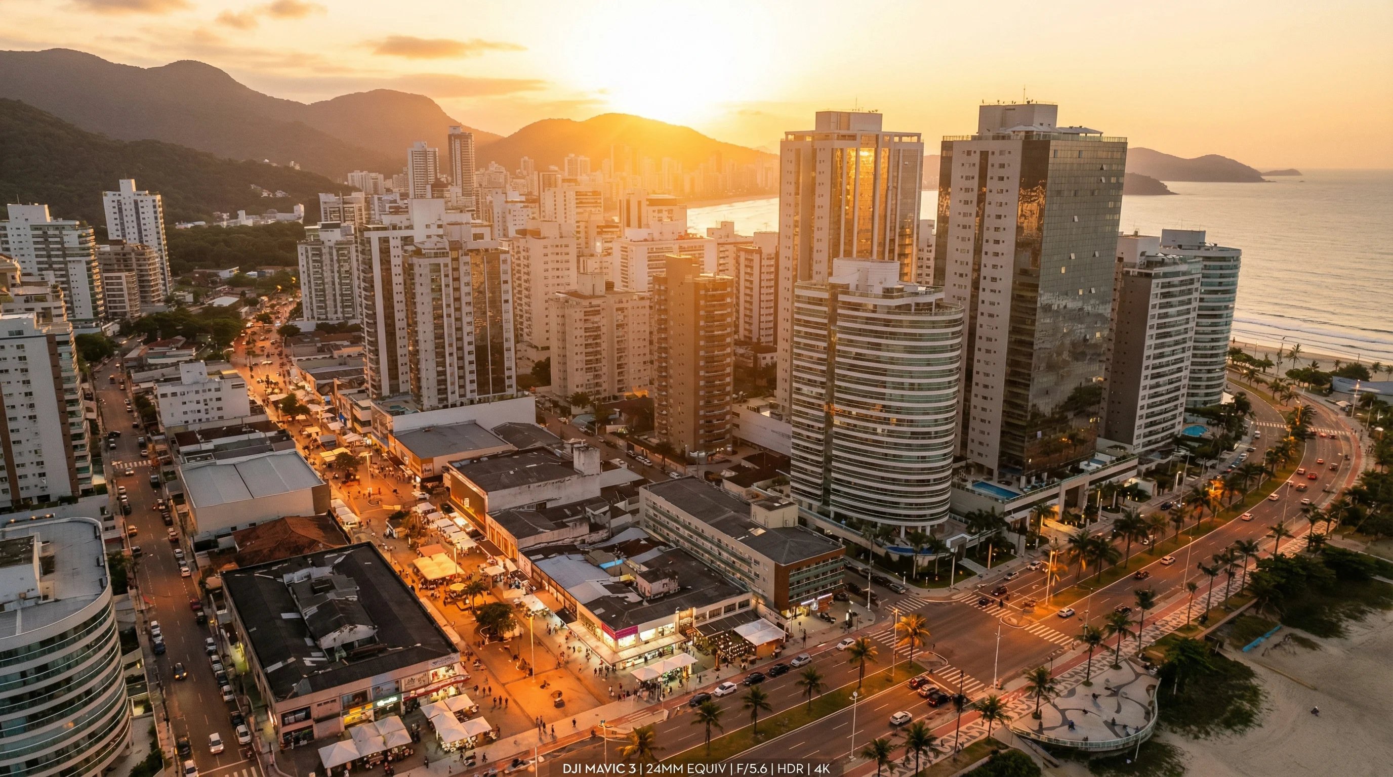 Vista aérea drone de cidade litorânea brasileira moderna ao pôr do sol dourado com prédios altos e ruas comerciais movimentadas