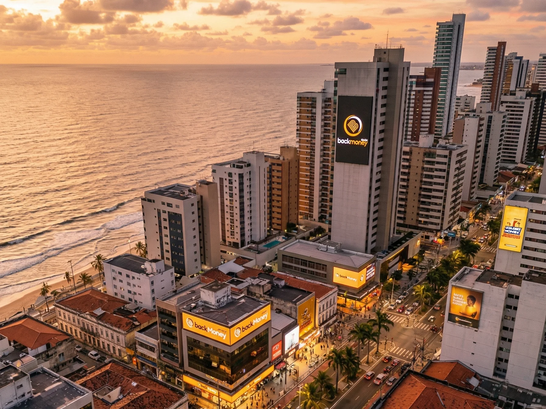Vista aérea drone de cidade litorânea brasileira ao pôr do sol dourado com outdoors BackMoney